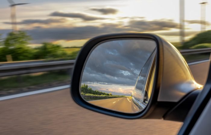 rearview mirror reflecting the highway and evening sky.
